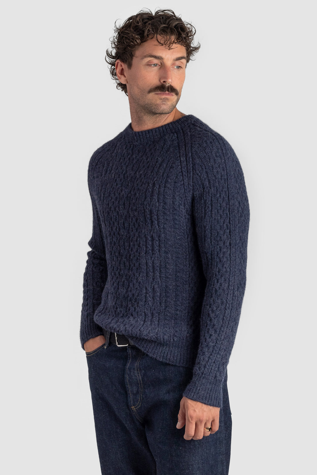 Man wearing a dark blue knitted sweater against a light gray background #colour_navy