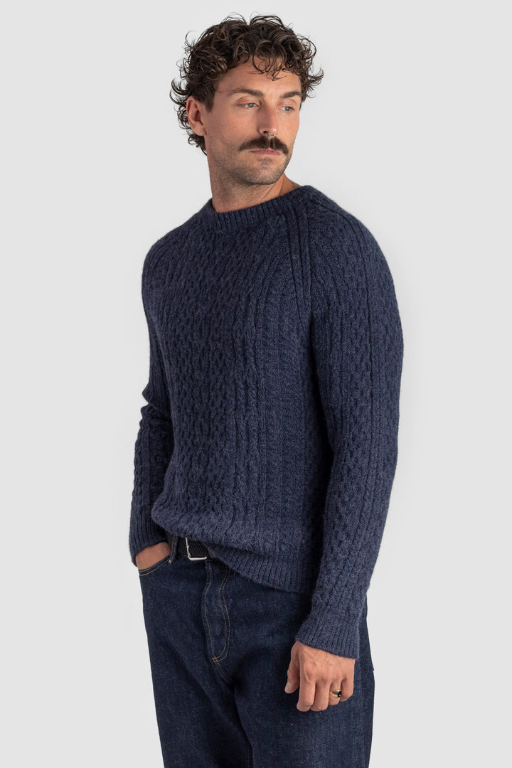 Man wearing a dark blue knitted sweater against a light gray background #colour_navy