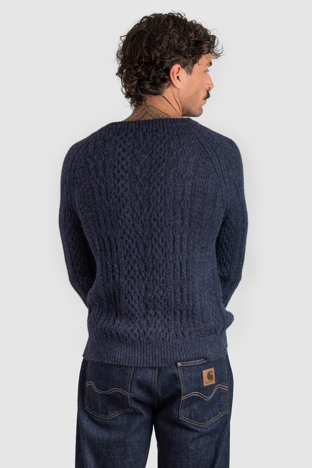 Man wearing a navy blue knitted sweater and jeans on a white background #colour_navy