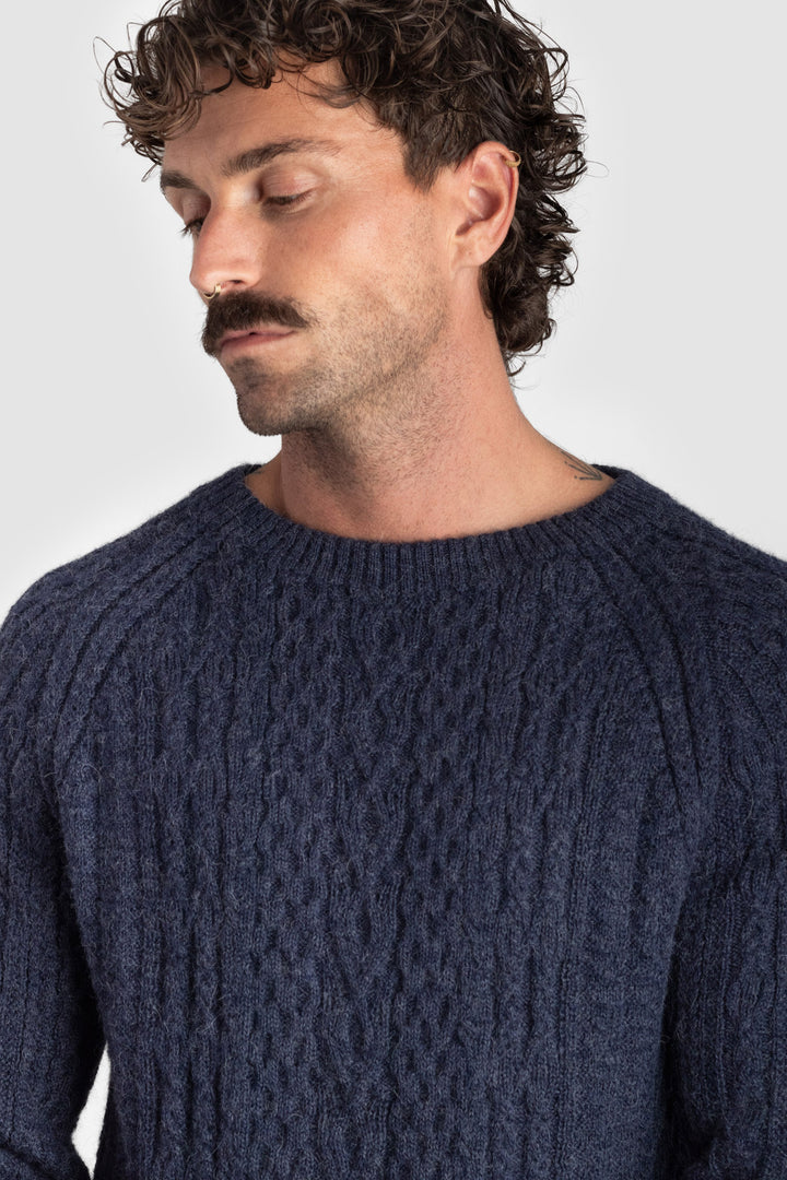 Man wearing a dark blue knitted sweater against a plain background #colour_navy