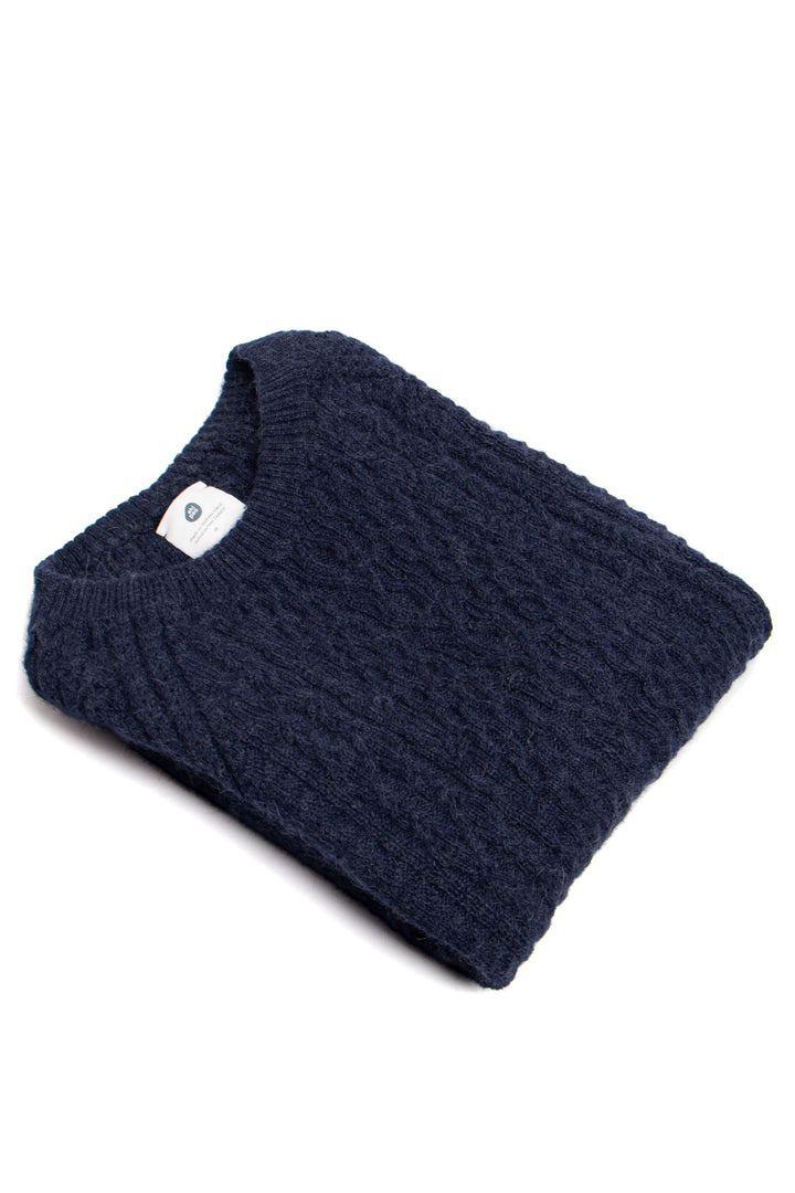 Folded navy blue sweater with a brand label on a white background #colour_navy