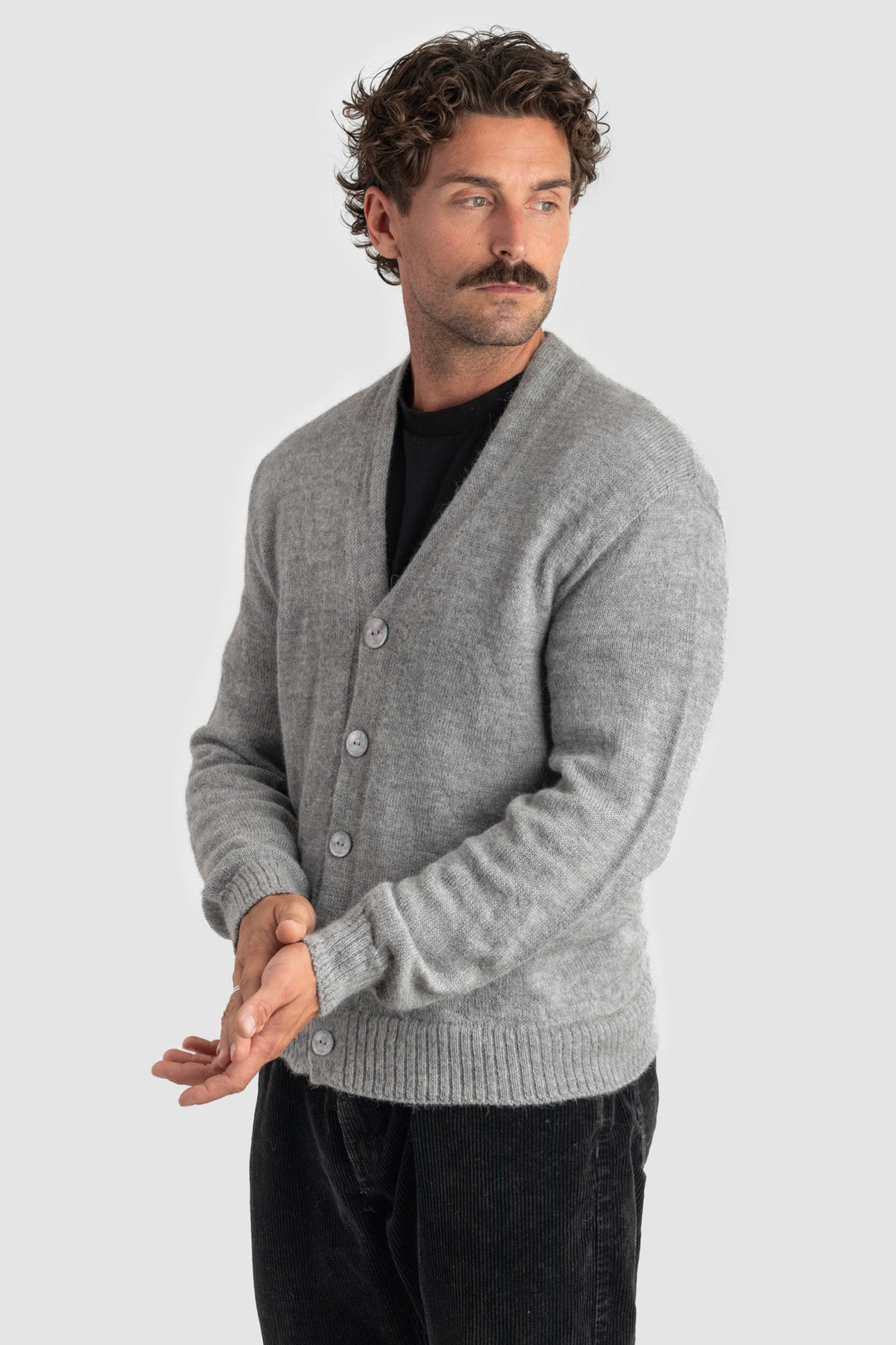 Man wearing a gray cardigan over a black shirt on a light gray background #colour_cool-grey