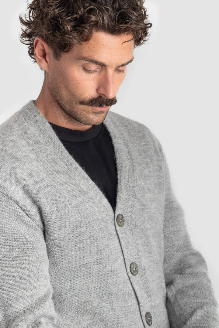 Man wearing a gray cardigan over a black shirt on a light gray background #colour_cool-grey