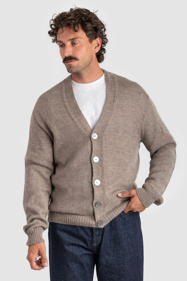 Man wearing a brown cardigan over a white shirt with a plain background #colour_fawn