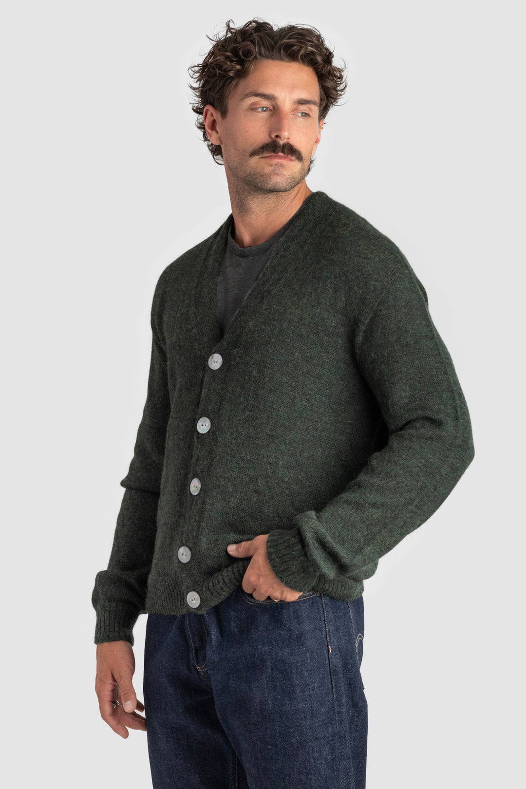 Man wearing a dark green cardigan over a black shirt on a light gray background #colour_pine