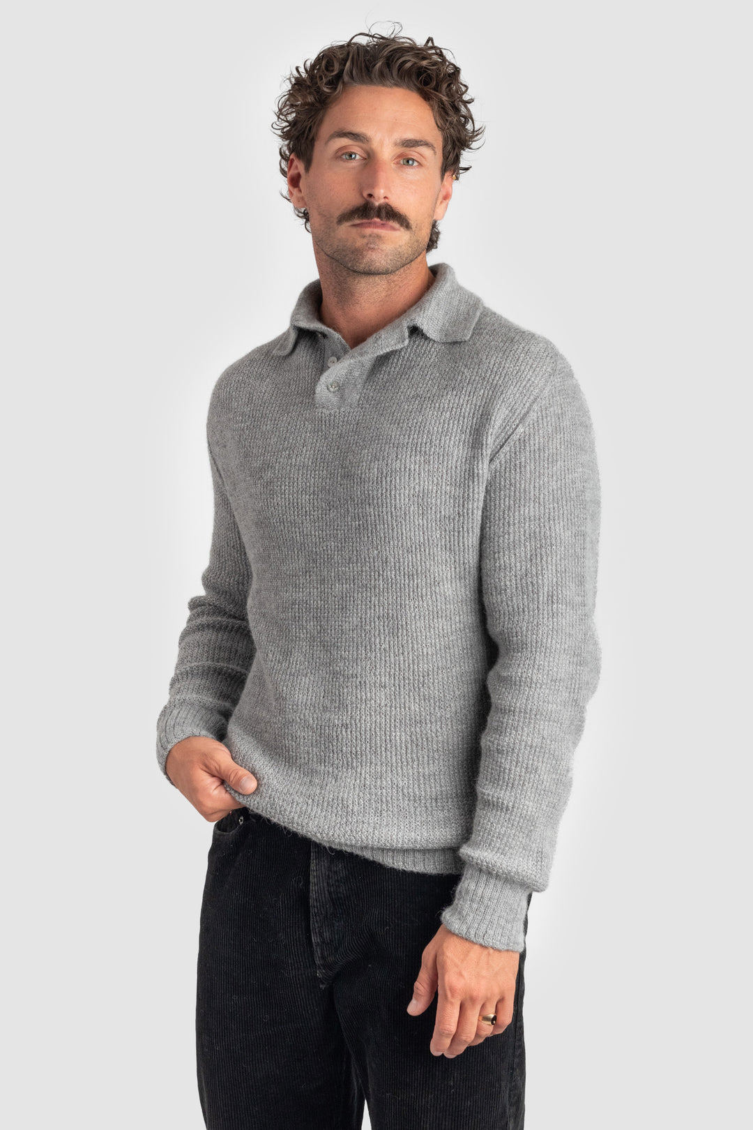Man wearing a gray sweater and black pants on a light gray background #colour_cool-grey