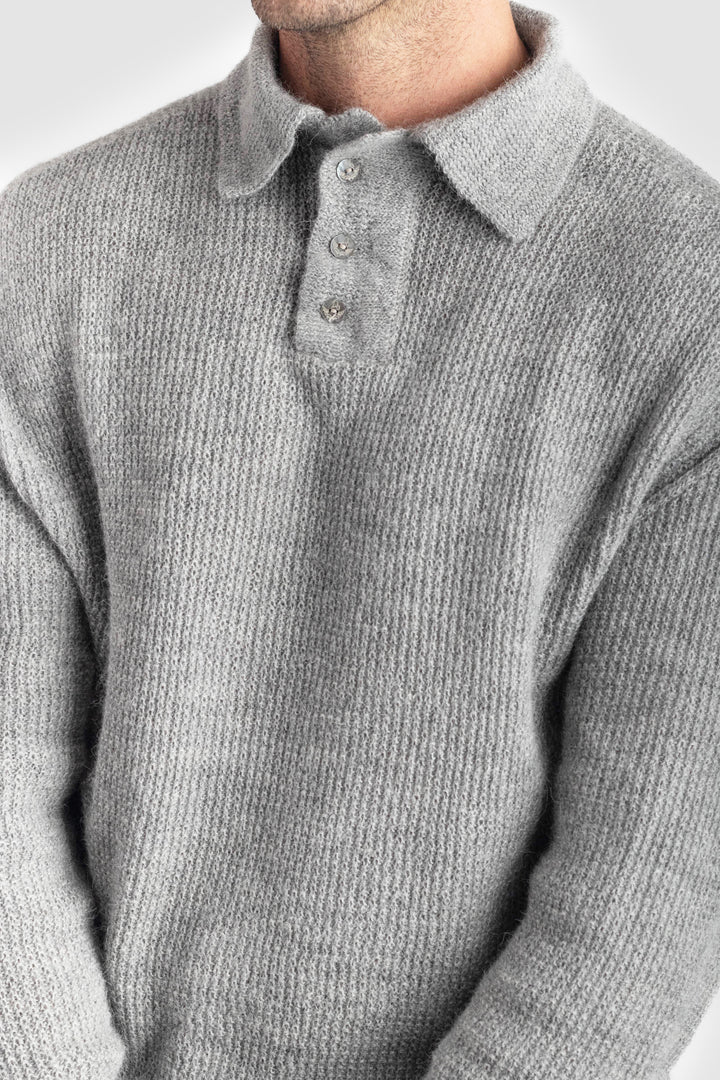 Close-up of a person wearing a gray knitted sweater with a collar. #colour_cool-grey