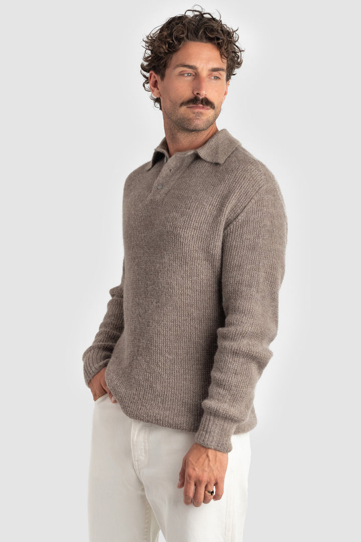 Man wearing a brown sweater and white pants on a light gray background #colour_fawn